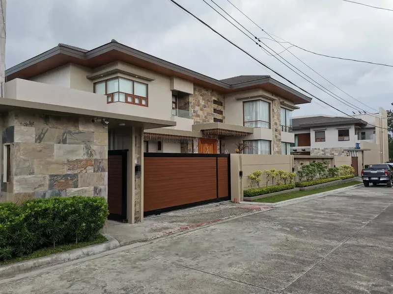 Two-storey house with a stone wall, timber gate and wide driveway