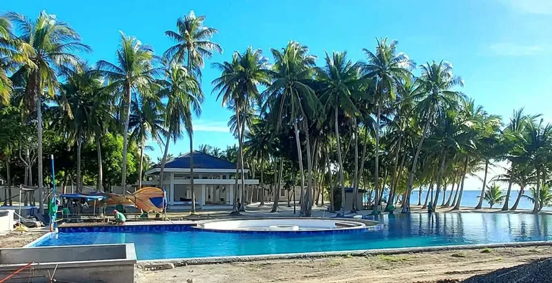 Beachfront resort pool with a clubhouse and palm trees