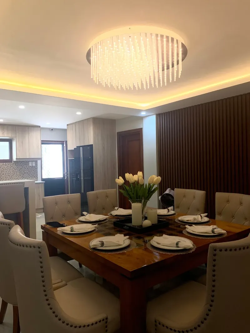 Dining room with a long timber table, upholstered chairs and a lit ceiling